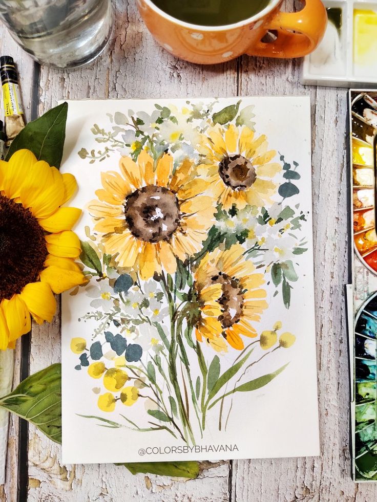 the sunflowers are painted on paper next to watercolor paints