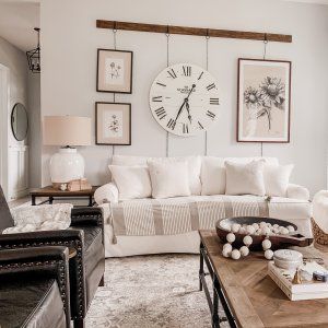 a living room filled with furniture and a large clock mounted to the wall above it