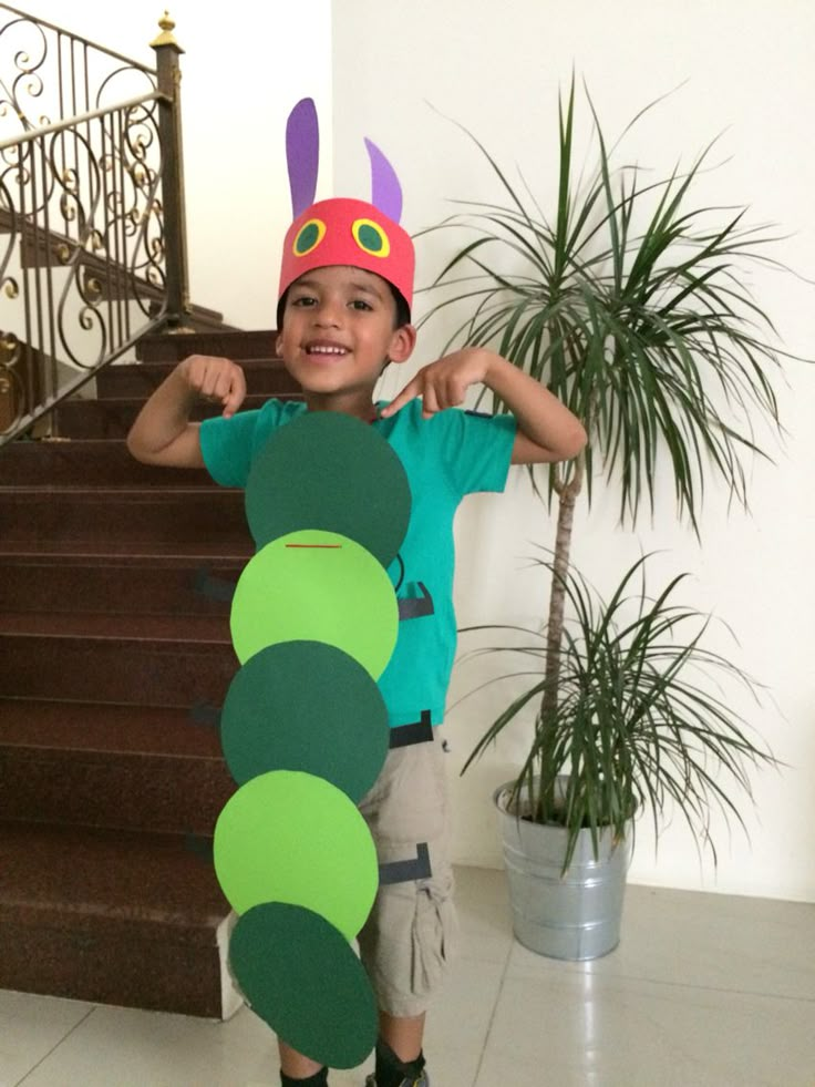 a young boy holding up a cardboard caterpillar