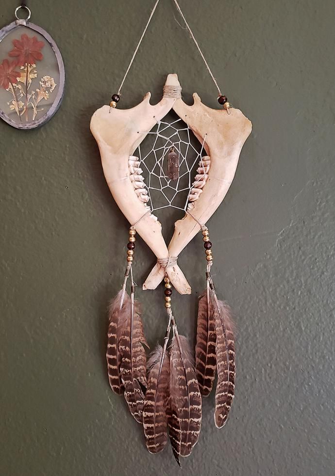 a piece of driftwood with feathers hanging from it's side next to a clock