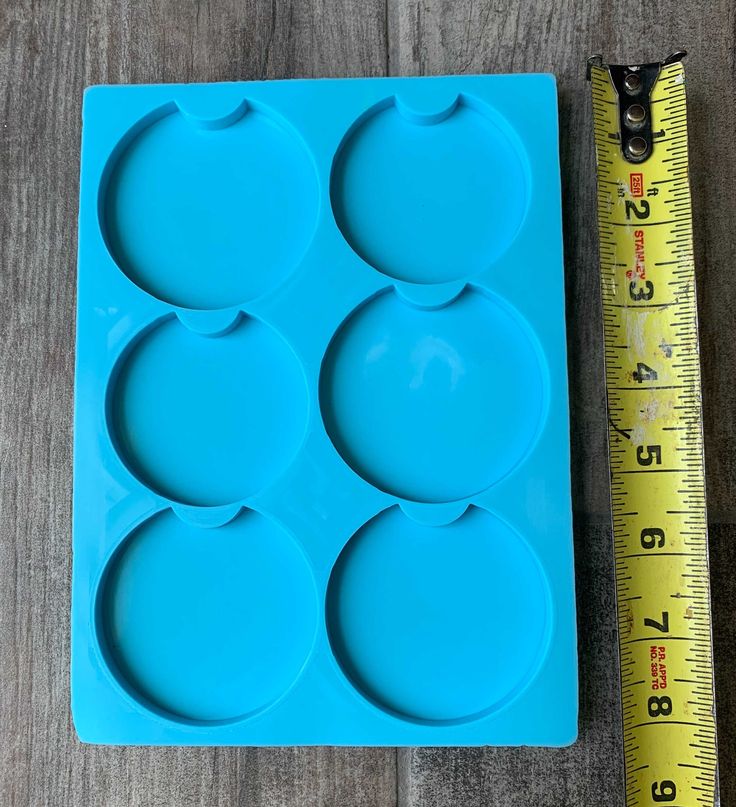 a blue tray with four circles on it next to a measuring tape