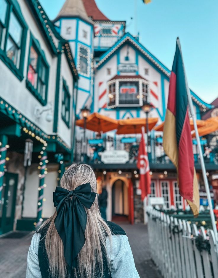 a woman with a black bow on her head is walking down the street in front of some buildings