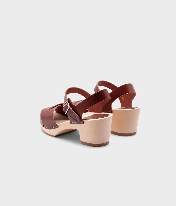 Embrace retro-inspired glamour with our high-heeled clog sandals, complete with an open-toe design that adds a modern twist to a classic silhouette. Perfect for pairing with your favorite dresses or jeans for a chic and stylish look. Clog measurements:Heel height: 2 5/8” (6.5 cm)Toe height: 1 1/2” (3.8 cm) Fit:NarrowLeather:Vegetable tanned leatherClogs consist of:Base: European Lime Wood Sole: Rubber sole Fastening: Staples Other: Metallic buckle Retro Open Toe Clogs For Summer, Retro Closed Toe Sandals With Wooden Heel, Retro Sandals With Wooden Open Heel, Chic Clogs With Wooden Heel And Ankle Strap, Chic Ankle Strap Clogs With Wooden Heel, Chic Block Heel Clogs With Padded Heel, Chic Clogs With Padded Block Heel, Chic Clogs With Ankle Strap And Buckle Closure, Retro Brown Clogs For Summer