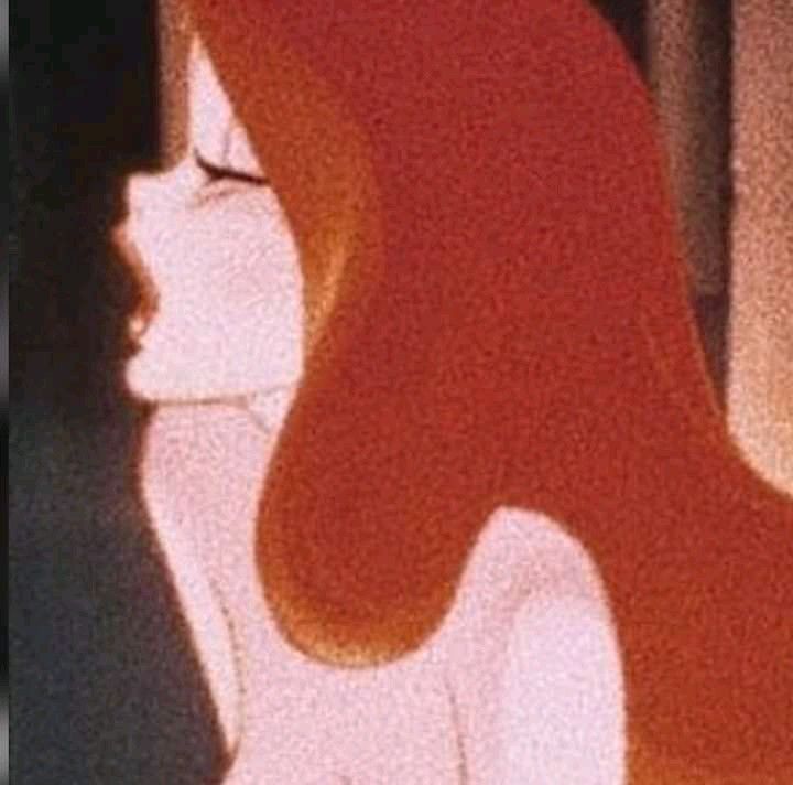 a woman with long red hair standing in front of a window