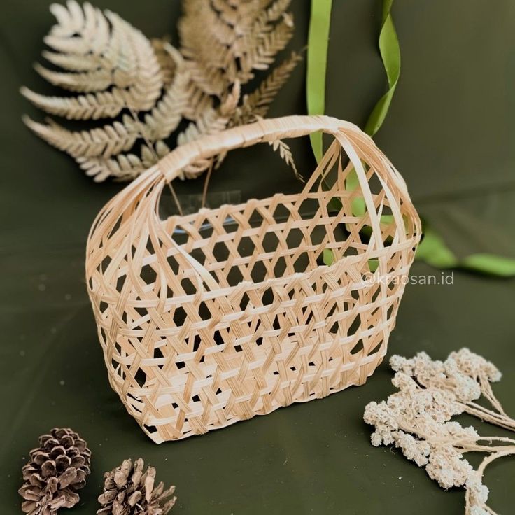 some pine cones are next to a basket on a green surface with leaves and flowers