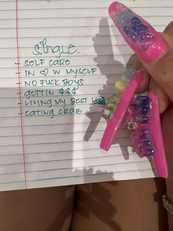 a person holding two pink toothbrushes with gummy bears on them and writing