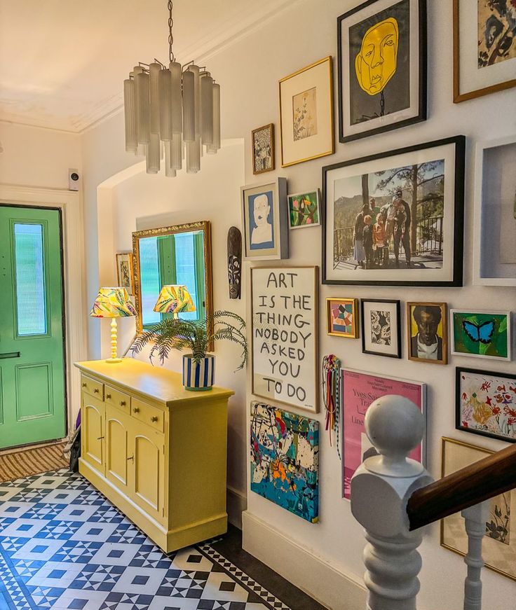 a room with pictures on the wall and paintings on the walls, along with a yellow dresser