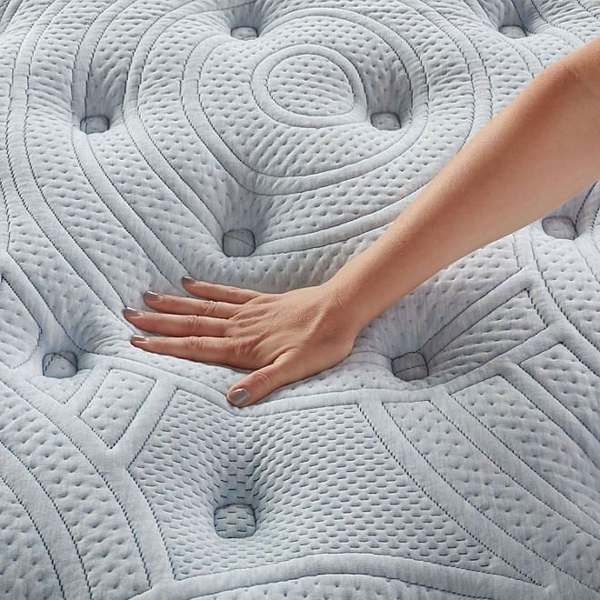 a person's hand on top of a mattress that is made in the shape of circles