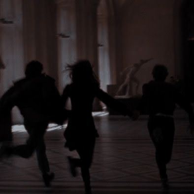 silhouettes of people running in an old building with columns and windows on either side