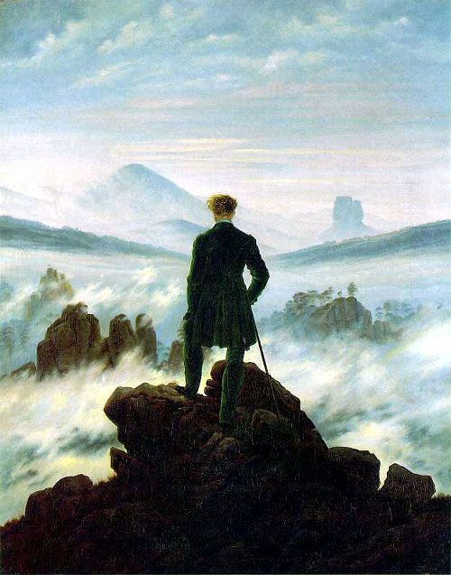 a man standing on top of a mountain in front of clouds