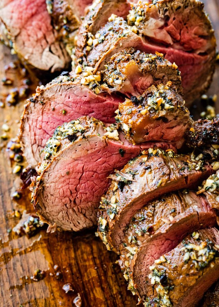 sliced steak on a cutting board with herbs and seasoning sprinkled on top