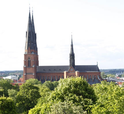 an old church with steeples and trees in the foreground