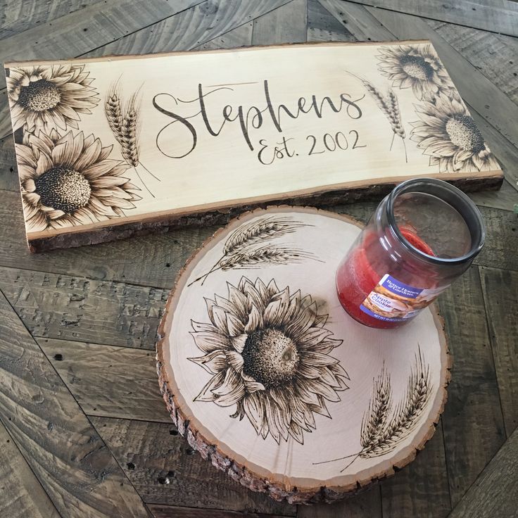 a wooden sign sitting on top of a table next to a jar of paint and a candle