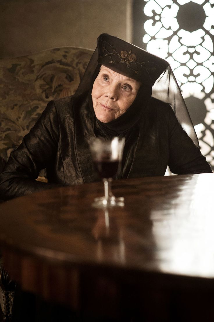 an older woman sitting at a table with a glass of wine