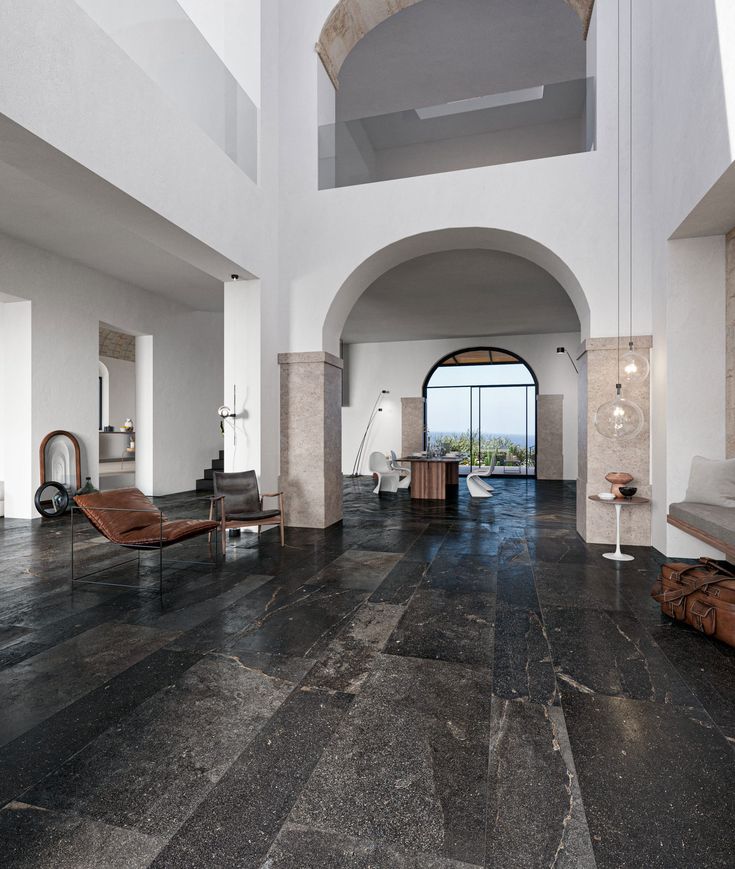 a large living room with black marble floors and white walls, along with an arched doorway that leads to the balcony