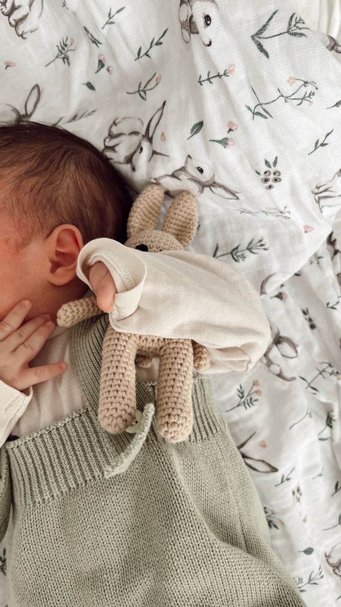 a baby sleeping on top of a bed next to a stuffed animal