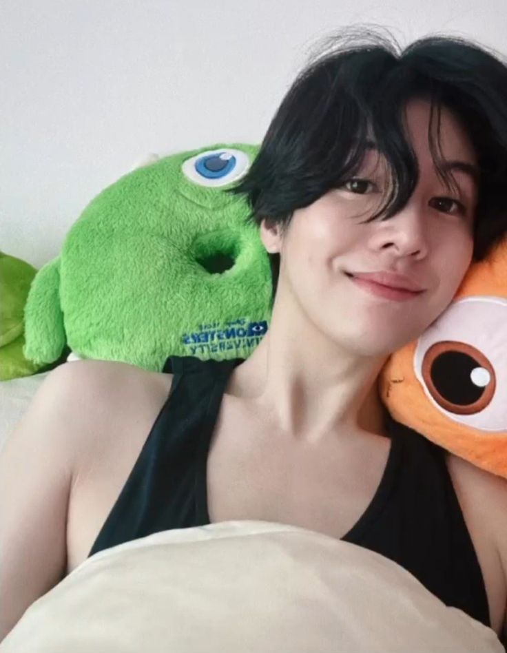 a woman laying in bed with two stuffed animals on her back and smiling at the camera