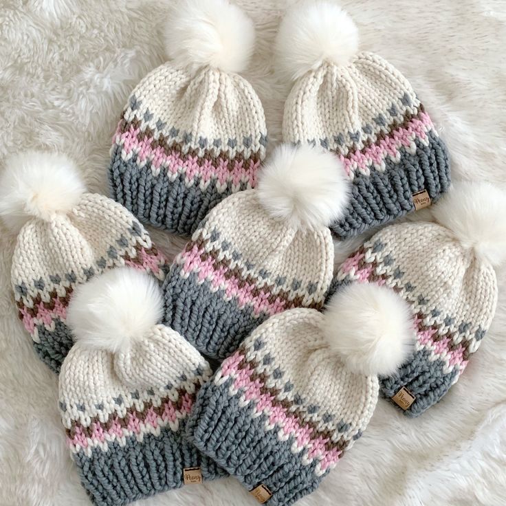 six knitted hats with white pom - poms are arranged in a circle