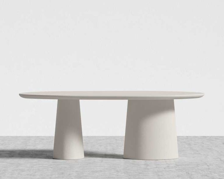 an oval table with two white pedestals sitting on top of each other in front of a wall