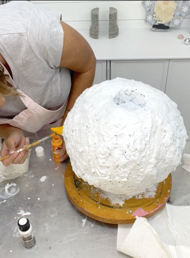 a woman is decorating a cake with white frosting and icing on it