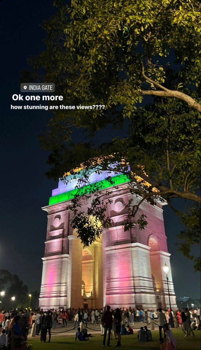 people are standing around in front of a large building with lights on it's sides