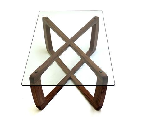 a glass and wood coffee table with an x design on the top, against a white background