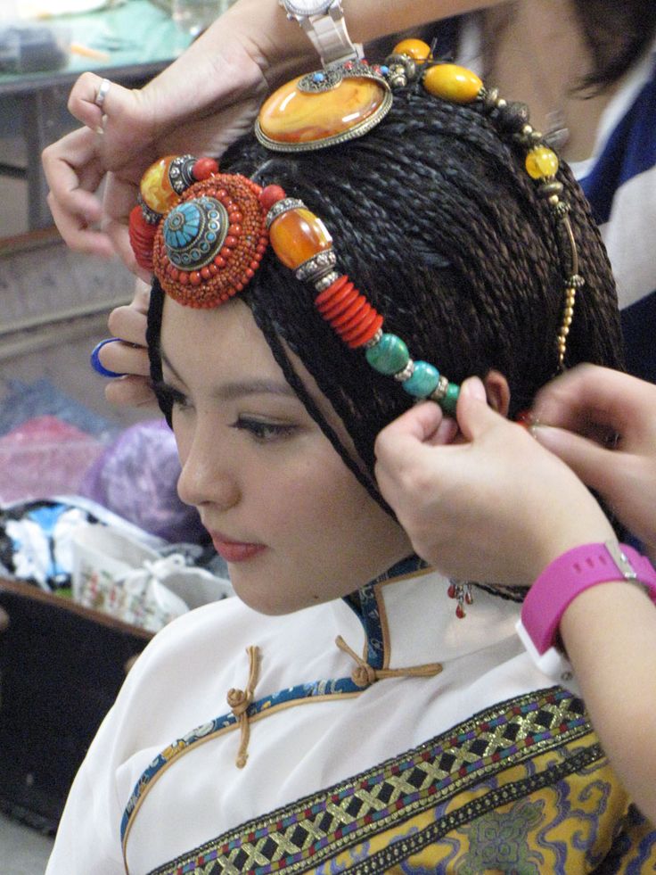 a woman is getting her hair done with beads and other items on her head,