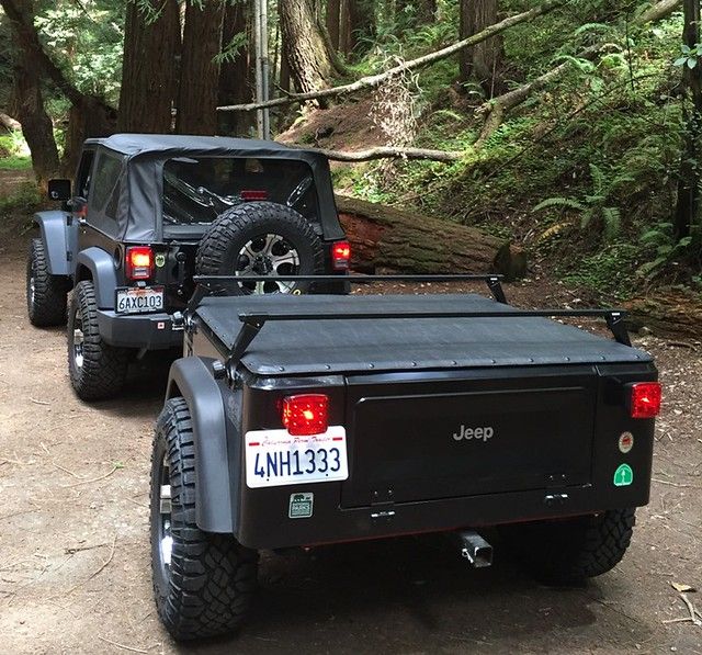 two jeeps are parked in the woods with their back lights on and one is off road