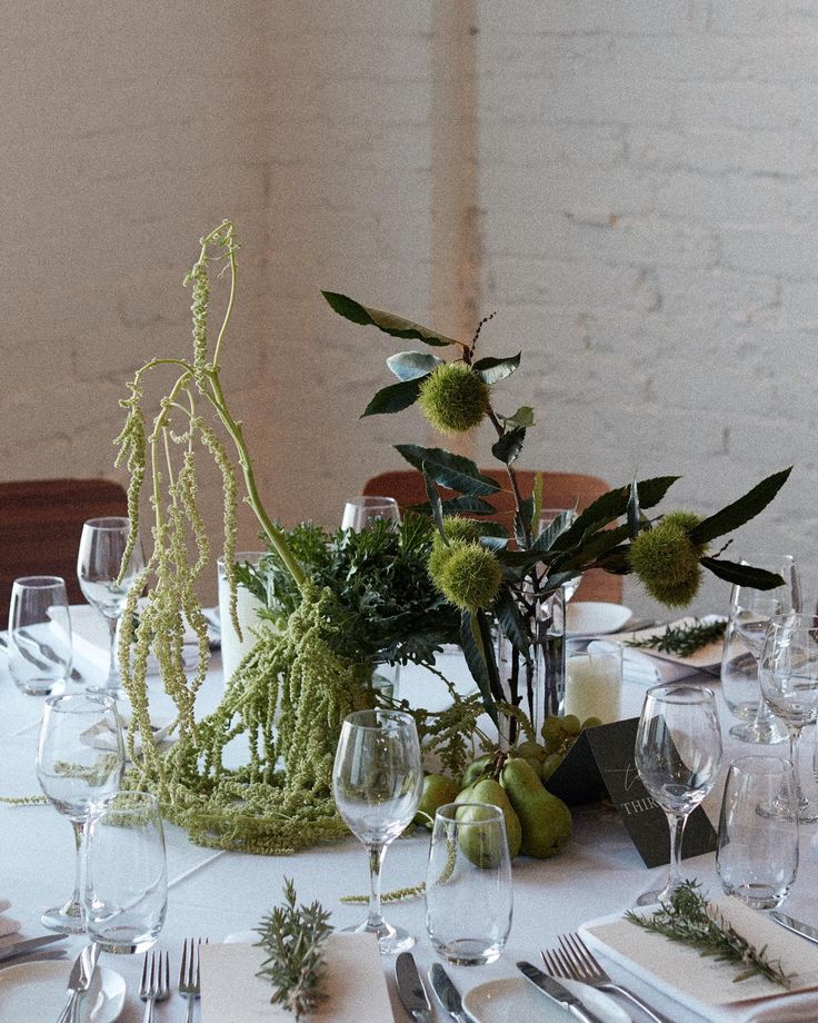 the table is set with silverware and green flowers