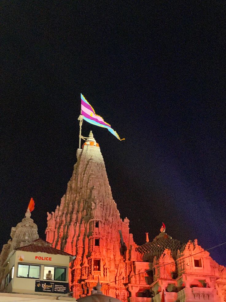 a large building with a rainbow flag flying in the air above it at night time