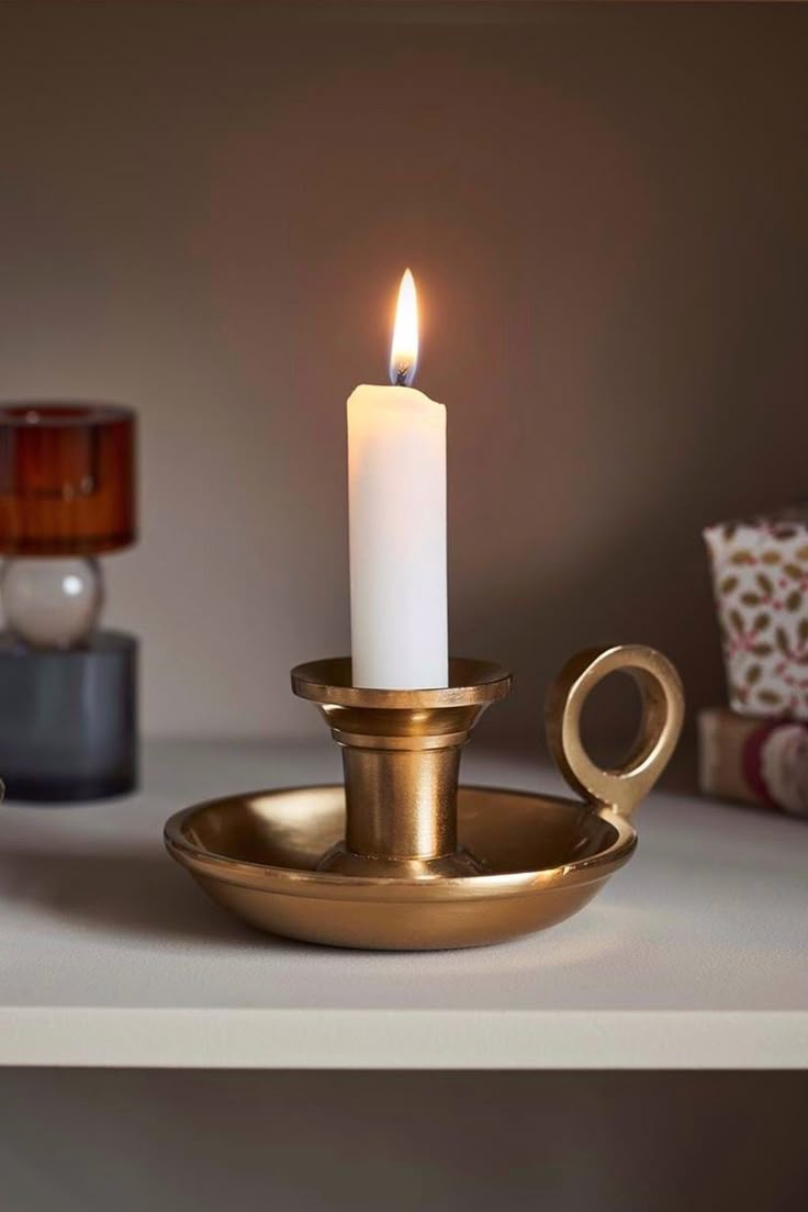 a lit candle sitting on top of a brass plate