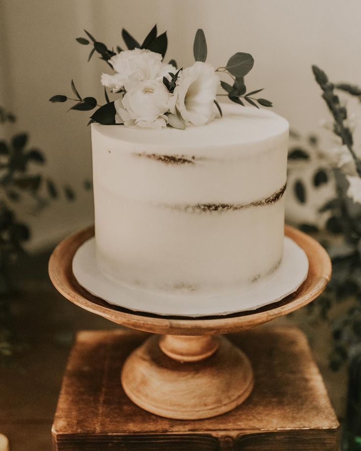 a white cake sitting on top of a wooden stand