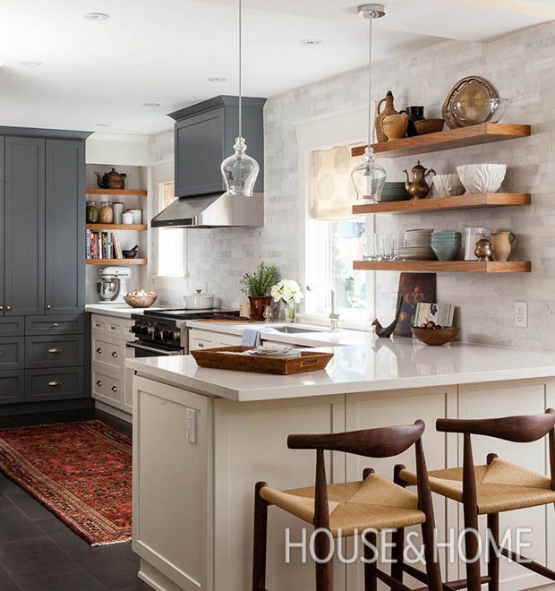 a kitchen with gray cabinets and white counter tops, two stools in front of the island