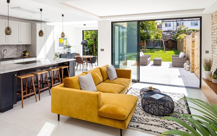 a living room filled with furniture next to a kitchen and an open floor plan in front of a sliding glass door