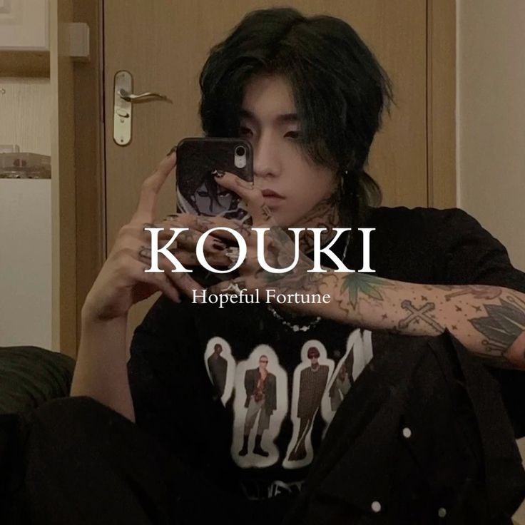 a man with black hair taking a selfie in front of a mirror while wearing a t - shirt that says koukki