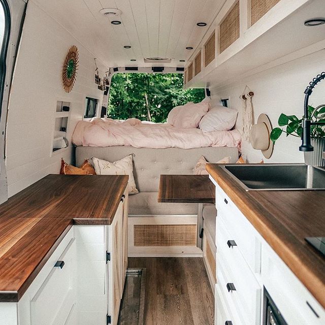 the interior of a camper with wood counter tops and white cupboards on both sides