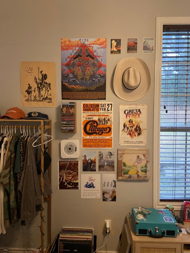 a room with posters, hats and other items hanging on the wall next to a window