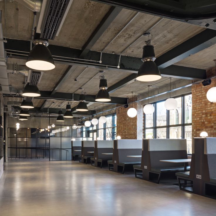 an empty room with tables and chairs in the center, lights hanging from the ceiling