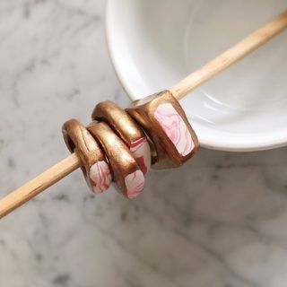 a wooden stick with pink and white designs on it sitting in front of a bowl