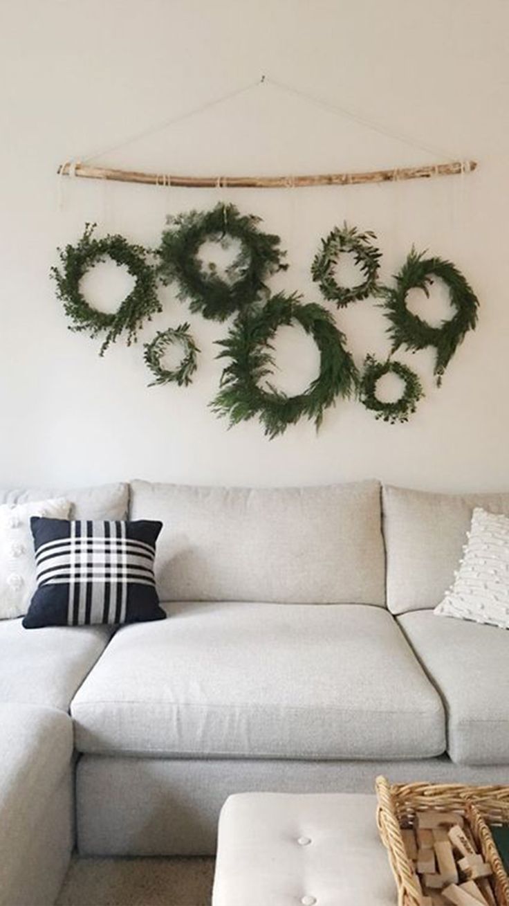 a living room with white couches and christmas wreaths on the wall above them