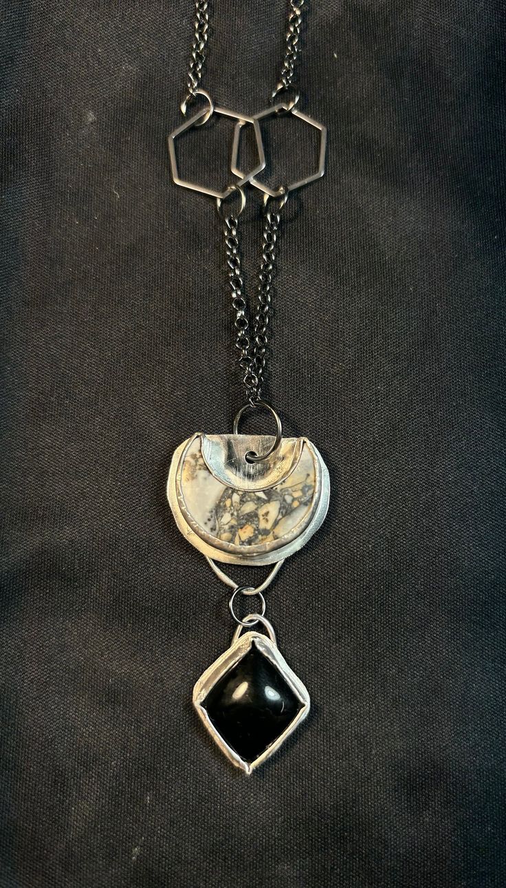 This is a grey Jasper crescent moon complimented by an diamond shaped Obsidian set in sterling silver. It's on a 26" gunmetal rolo chain with hexagon details. Black Crescent Metal Jewelry, Black Metal Crescent Jewelry, Modern Black Jewelry With Oxidized Finish, Modern Black Oxidized Jewelry, Black Hand Forged Spiritual Necklace, Artisan Black Pendant Jewelry, Artisan Silver Crescent Jewelry, Artisan Crescent Silver Jewelry, Unique Black Agate Jewelry