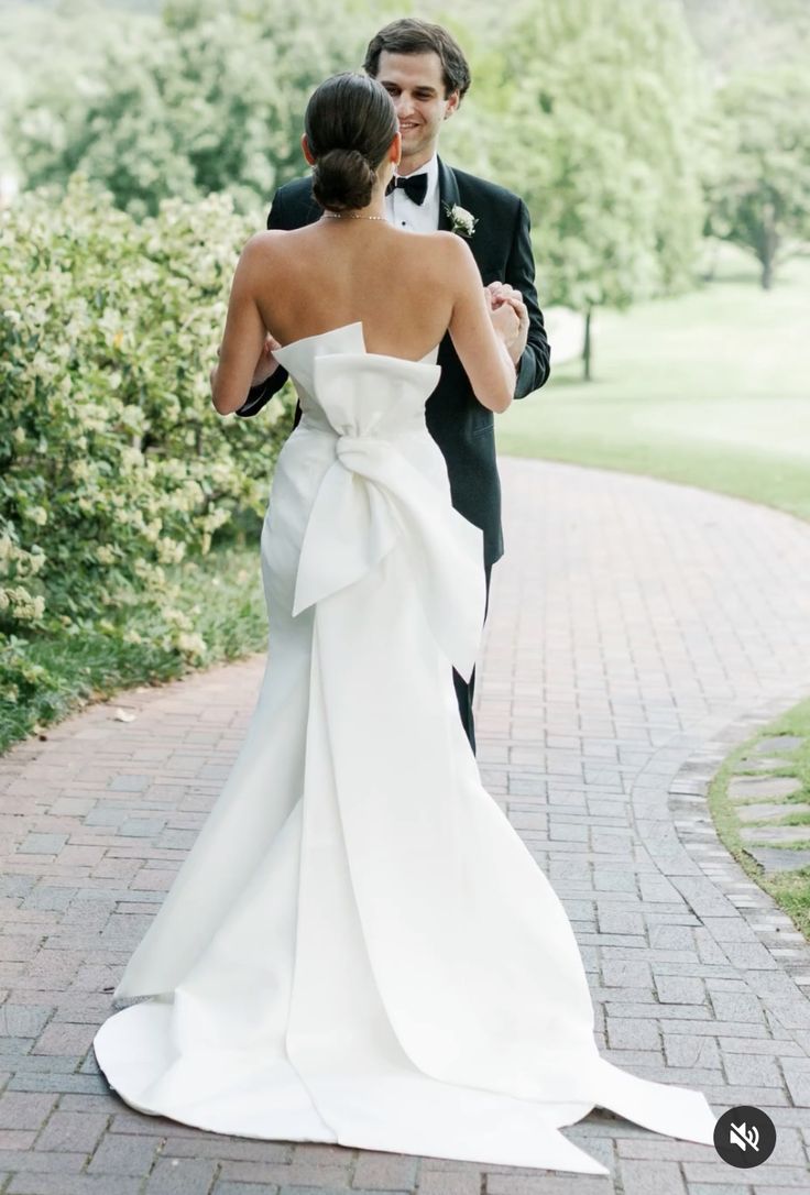 a bride and groom walking down a brick path