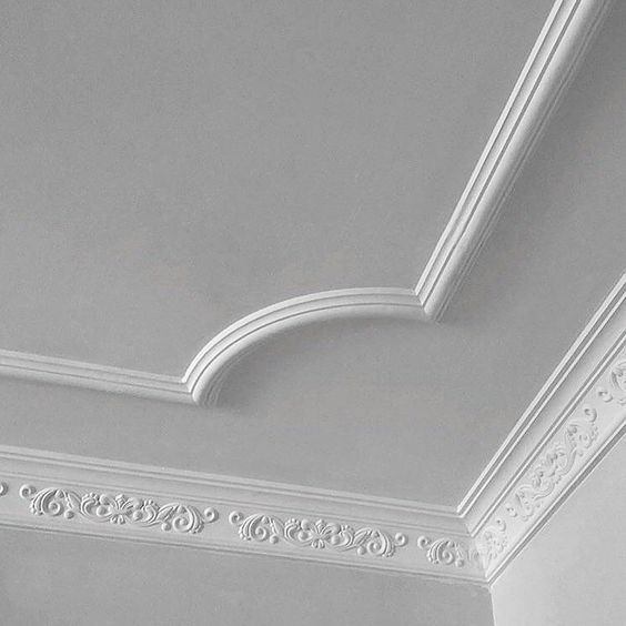 the ceiling is painted white and has decorative moldings on it, along with a clock