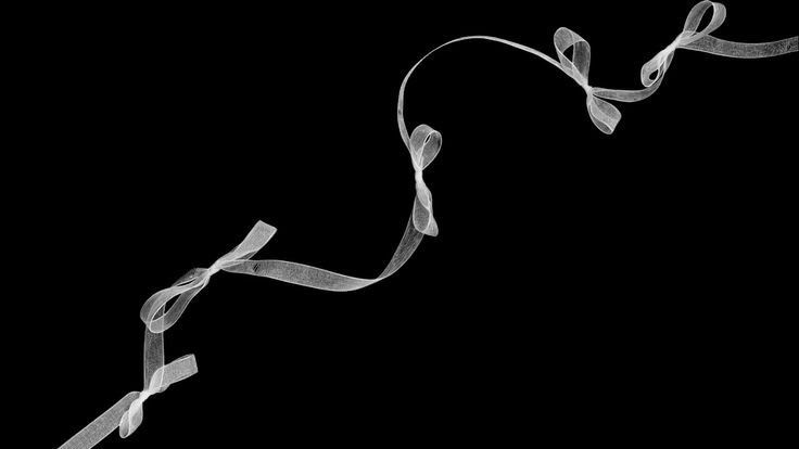 a black and white photo of a ribbon on a black background with the word love spelled below it