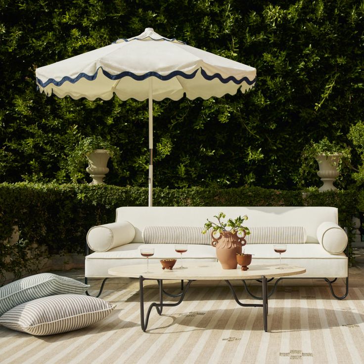 a white couch sitting on top of a wooden floor next to a table and umbrella