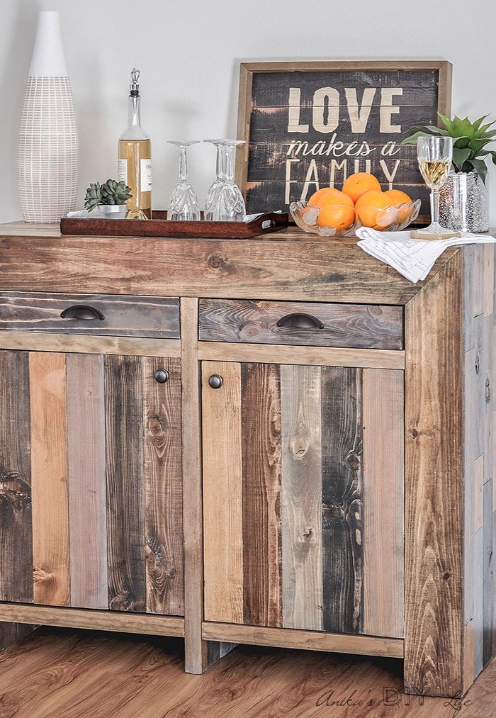 a wooden buffet table topped with oranges and wine glasses