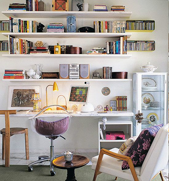 a living room filled with furniture and lots of books on the shelves above it's desk