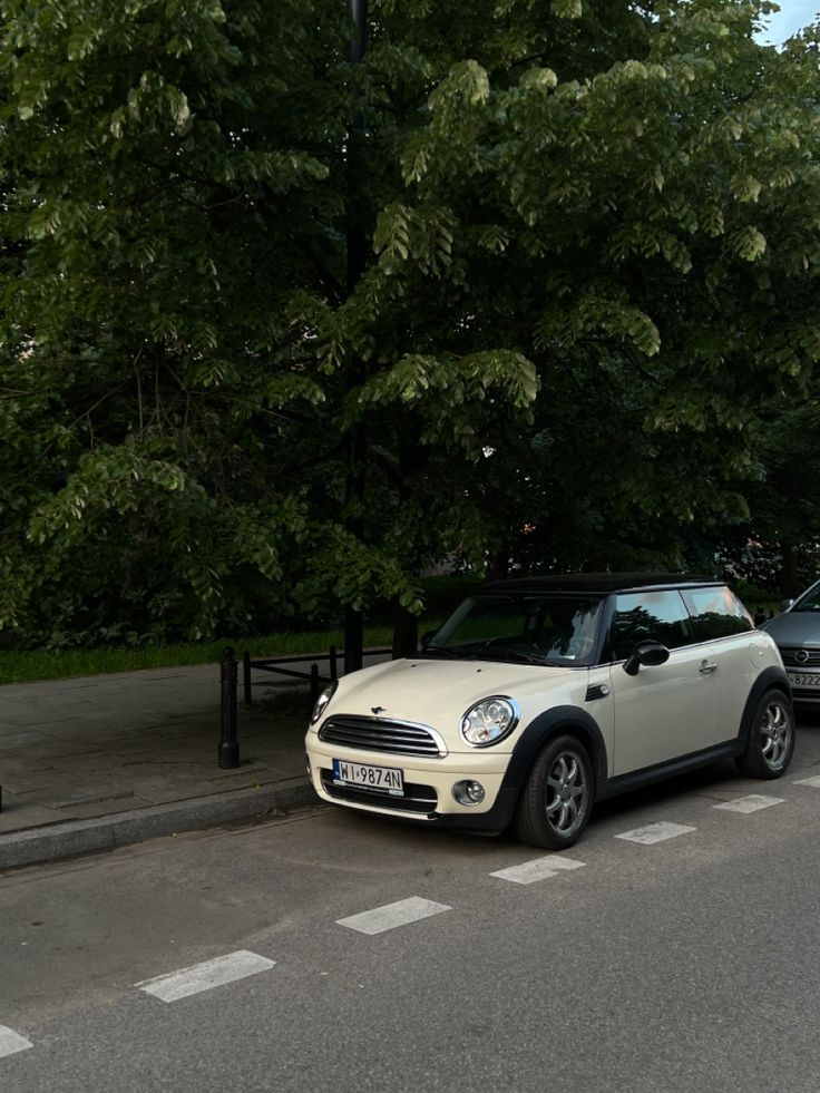 two cars are parked on the side of the road next to a bench and trees