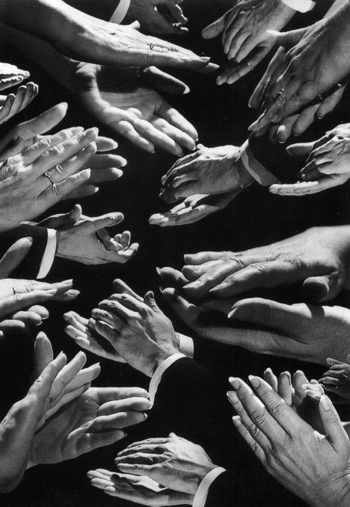 black and white photograph of many hands reaching towards each other