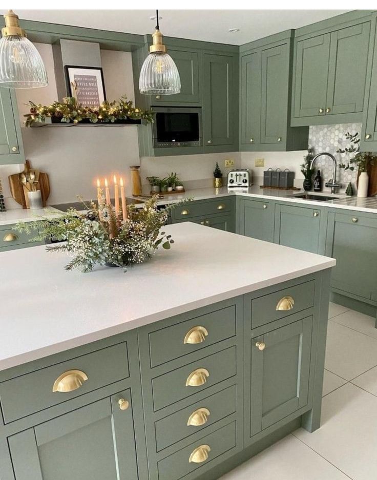 a kitchen filled with lots of green cabinets and white counter tops covered in christmas lights